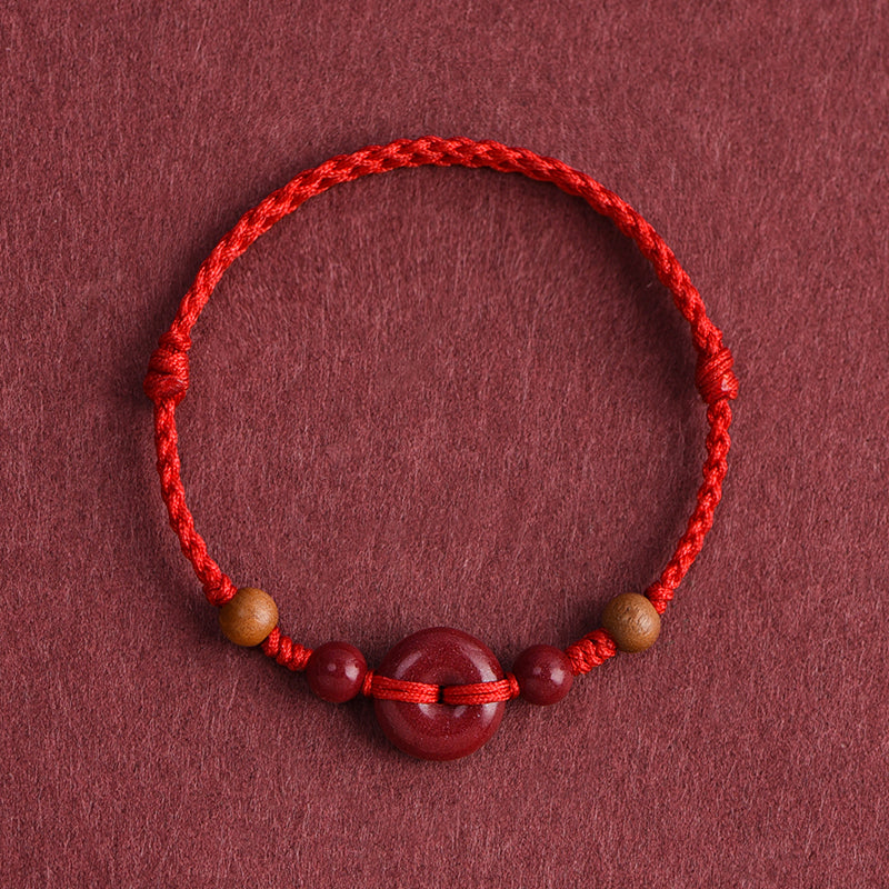 Red String Bracelet with Cinnabar Safety Buckle on a maroon background